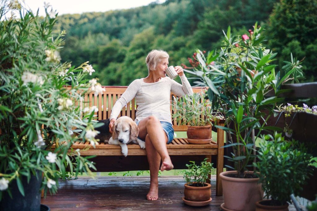 senior woman drinking coffee on a bench with her dog