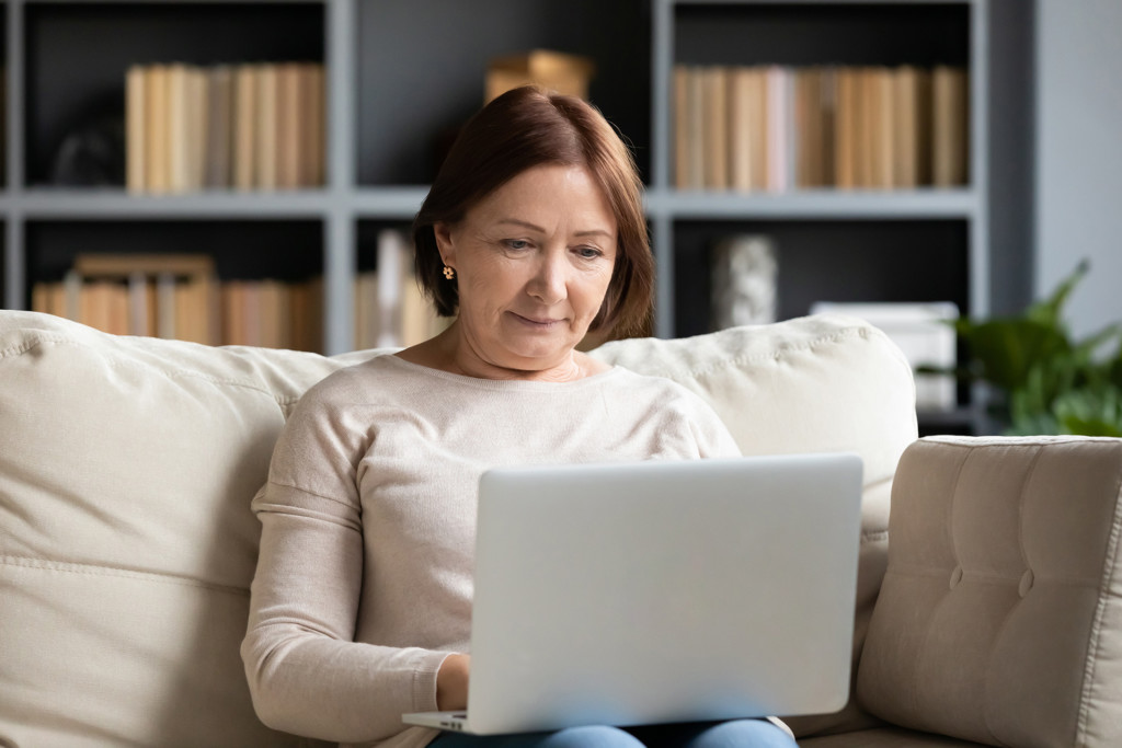 Concentrated pleasant mature older woman looking at computer screen.