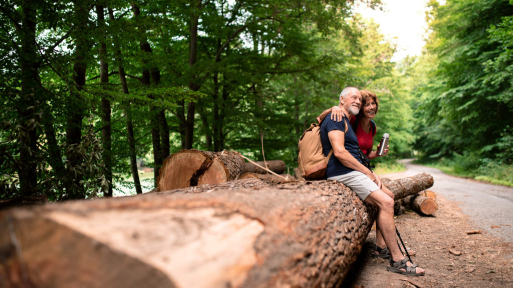 senior couple hiking together resting on a log