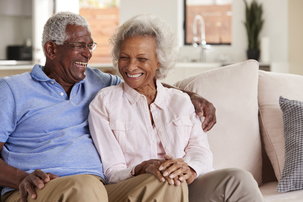 Loving Senior Couple Sitting On Sofa At Home And Laughing Together