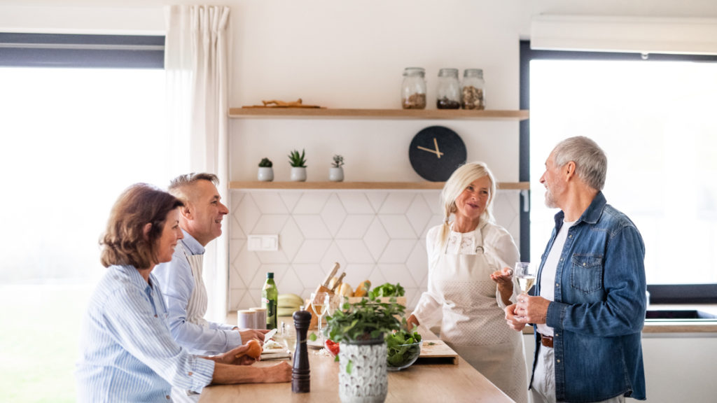 two senior couple drinking wine together in kitchen