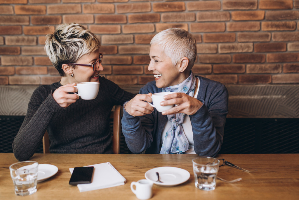 Senior mother sitting in cafe bar or restaurant with her middle age daughter and enjoying in conversation