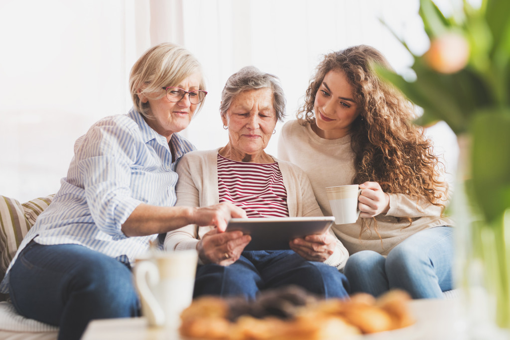 A teenage girl, mother and grandmother at home using a tablet