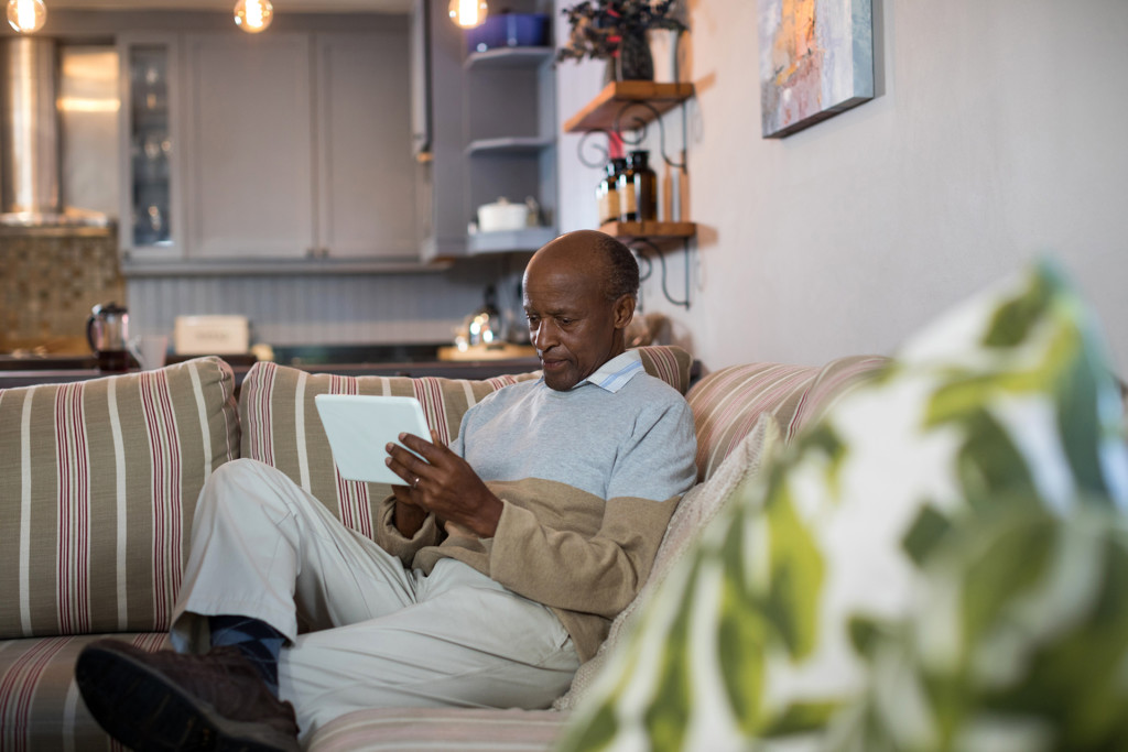 Senior man using tablet computer in living room